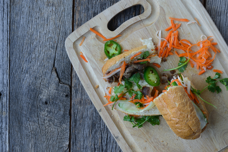 Vietnamese Grilled Pork Banh Mi Sandwich on Rustic Wood Backgroundの写真素材