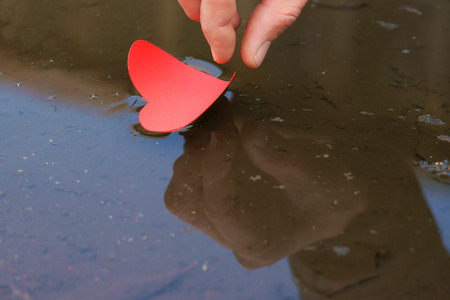 Paper shaped heart in water stream with handの写真素材