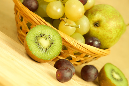 Cutted kiwi and fruits basketの写真素材