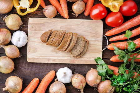 Bread on the wooden cutting board with vegetablesの写真素材