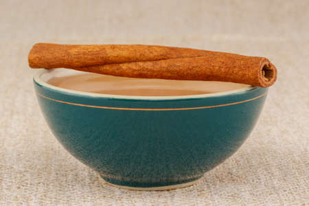 Honey in green porcelain bowl, with cinnamon sticks on rustic table clothの写真素材