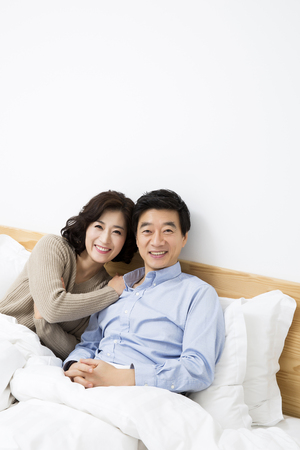 Middleaged Asian Couple Smiling in Bedの写真素材