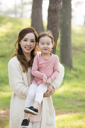 Happy Asian Mother and Daughter Smiling,Posing in Forest,Mother Carrying Daughterの写真素材