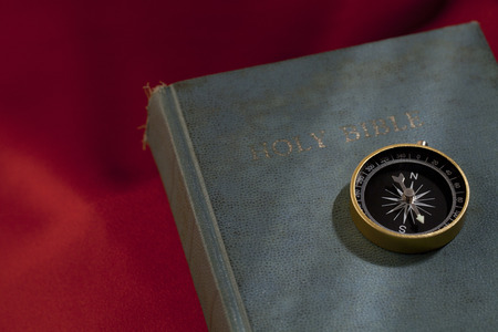Closed holy bible with a compass placed on the coverの写真素材