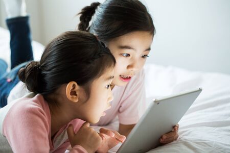Young Children Studying On Bedの写真素材