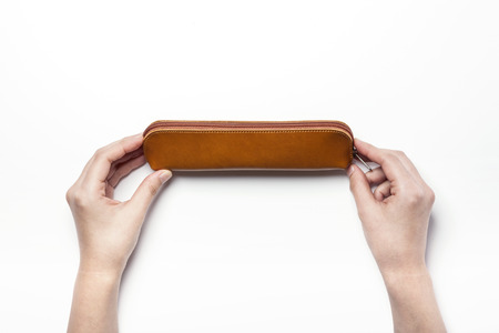 A leather pencil case with two hands - isolated on whiteの写真素材
