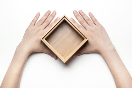 Close up shot of hands holding a wooden box/container-isolated on whiteの写真素材