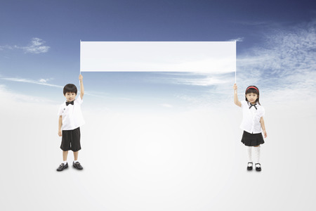 Asian kids holding up a white bannerの写真素材