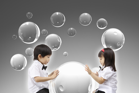 Asian kids looking down at 3d bubblesの写真素材