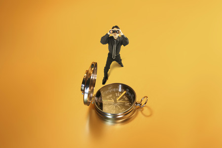 Asian business man with binoculars and a compassの写真素材