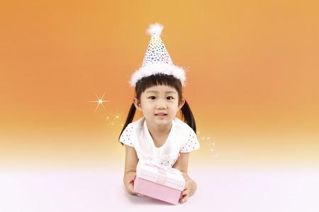 Cute little Asian girl with a party hat and a gift boxの写真素材