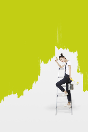 Asian girl painting green on the wallの写真素材