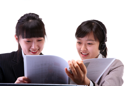 Two Asian business women working with headsetの写真素材