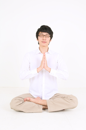 Young Asian man sitting and stretching - isolated on whiteの写真素材