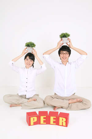 Young Asian couple sitting with words made with alphabet blocks - isolated on whiteの写真素材