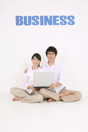 Young Asian couple looking at a laptop - isolated on whiteの写真素材