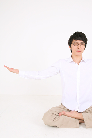 Young Asian man sitting and stretching - isolated on whiteの写真素材