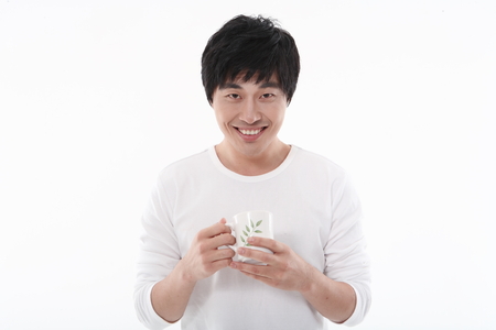 Young Asian man holding a glass of water - isolated on whiteの写真素材
