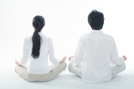 Young Asian couple sitting and meditating in the studio - isolated on whiteの写真素材