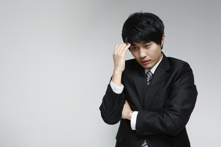 Young Asian man in suit smiling, posing in the studio - isolated on whiteの写真素材