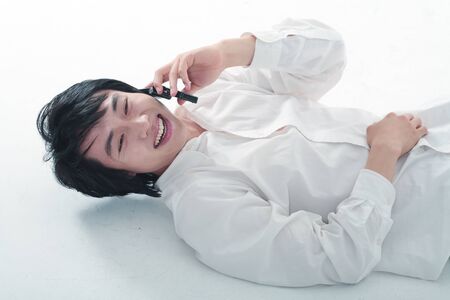 Young Asian man on his phone - isolated on whiteの写真素材