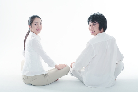 Young Asian couple sitting and meditating in the studio - isolated on whiteの写真素材
