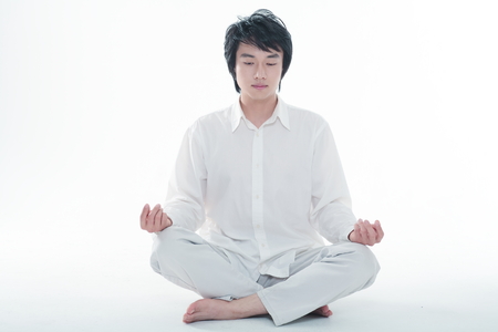 Young Asian man meditating - isolated on whiteの写真素材