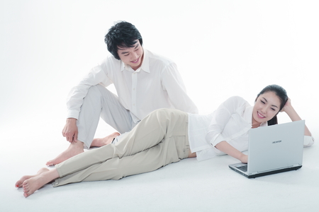 Young Asian couple with a phone and a laptop - isolated on whiteのeditorial素材