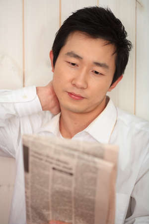 Asian man reading newspaperの写真素材