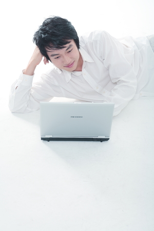 Young Asian man on his laptop - isolated on whiteのeditorial素材
