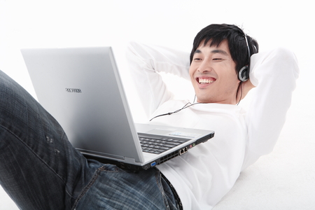 Young Asian man lying down with his laptop - isolated on whiteのeditorial素材