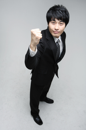 Young Asian man in suit smiling, posing in the studio - isolated on whiteの写真素材