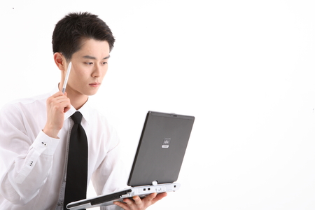 Asian businessman working on his laptop - isolated on whiteの写真素材