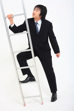 Asian businessman posing  with a ladder in the studio- isolated on whiteの写真素材