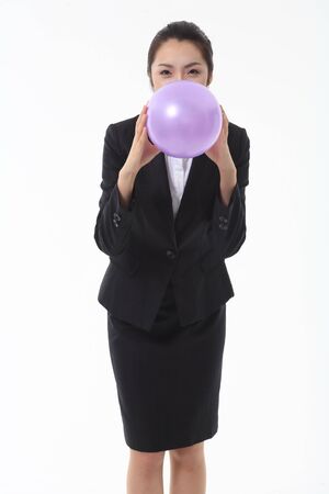 Asian businesswoman blowing a balloon - isolated on whiteの写真素材