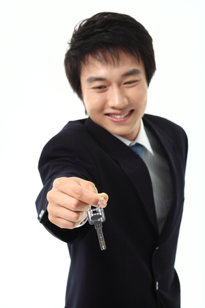 Asian businessman holding a key - isolated on whiteの写真素材