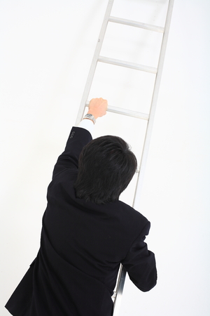 Asian businessman posing  with a ladder in the studio- isolated on whiteの写真素材