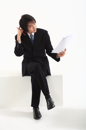 Asian businessman looking at the documents - isolated on whiteの写真素材