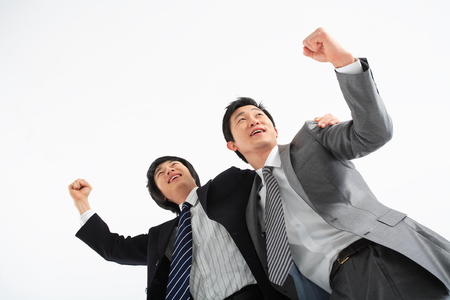 Two Asian businessmen putting arms around each other's shoulders - isolated on whiteの写真素材