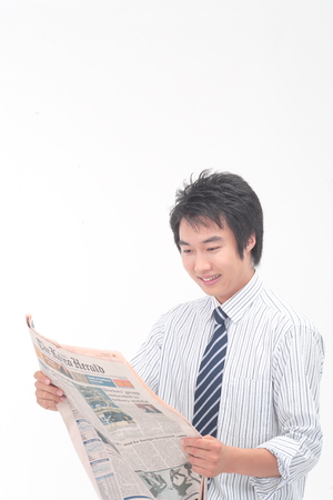 Asian businessman reading newspaper - isolated on whiteの写真素材