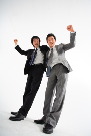 Two Asian businessmen putting arms around each other's shoulders - isolated on whiteの写真素材