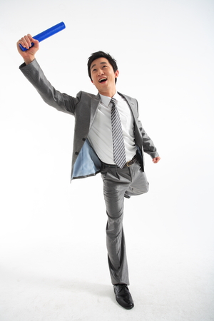 Asian businessman running with a relay baton - isolated on whiteの写真素材