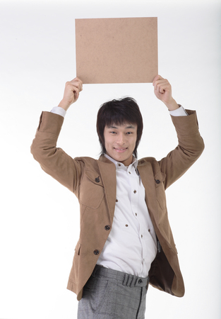 Young Asian man holding a blank board - isolated on whiteの写真素材