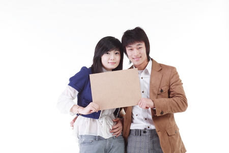 Young Asian couple holding a blank board - isolated on whiteの写真素材