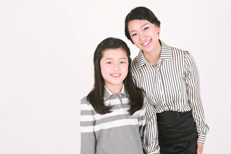 An asian girl and a woman stading with smile - isolated on whiteの写真素材