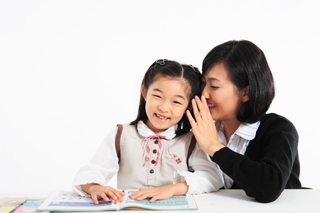 An smiling asian girl studying with a teacher - isolated on whiteの写真素材