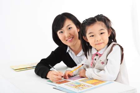An smiling asian girl studying with a teacher - isolated on whiteの写真素材