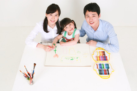 Adults and a little girl drawing with crayons - isolated on whiteの写真素材