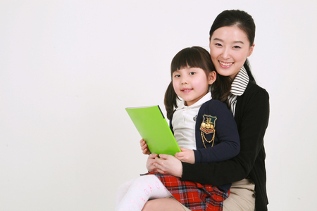 A female teacher reading a book to a little girlのeditorial素材