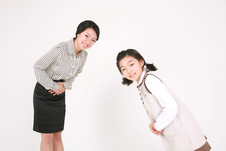 An asian girl and woman bowing their head in greeting- isolated on whiteの写真素材